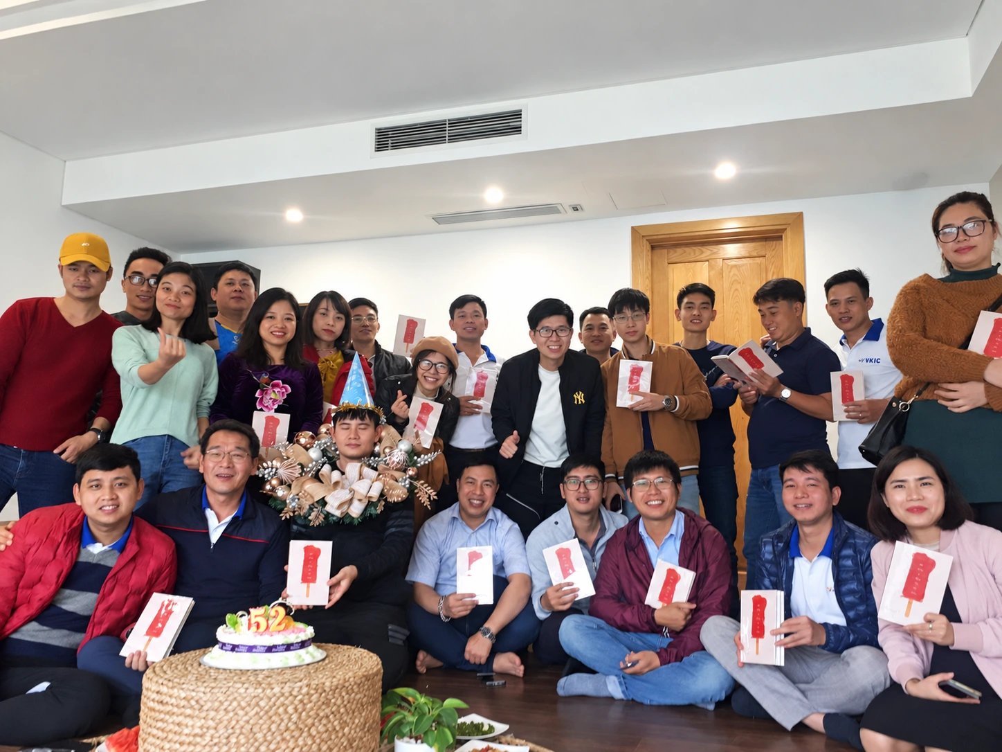 Colleagues gathered around a birthday cake with gifts